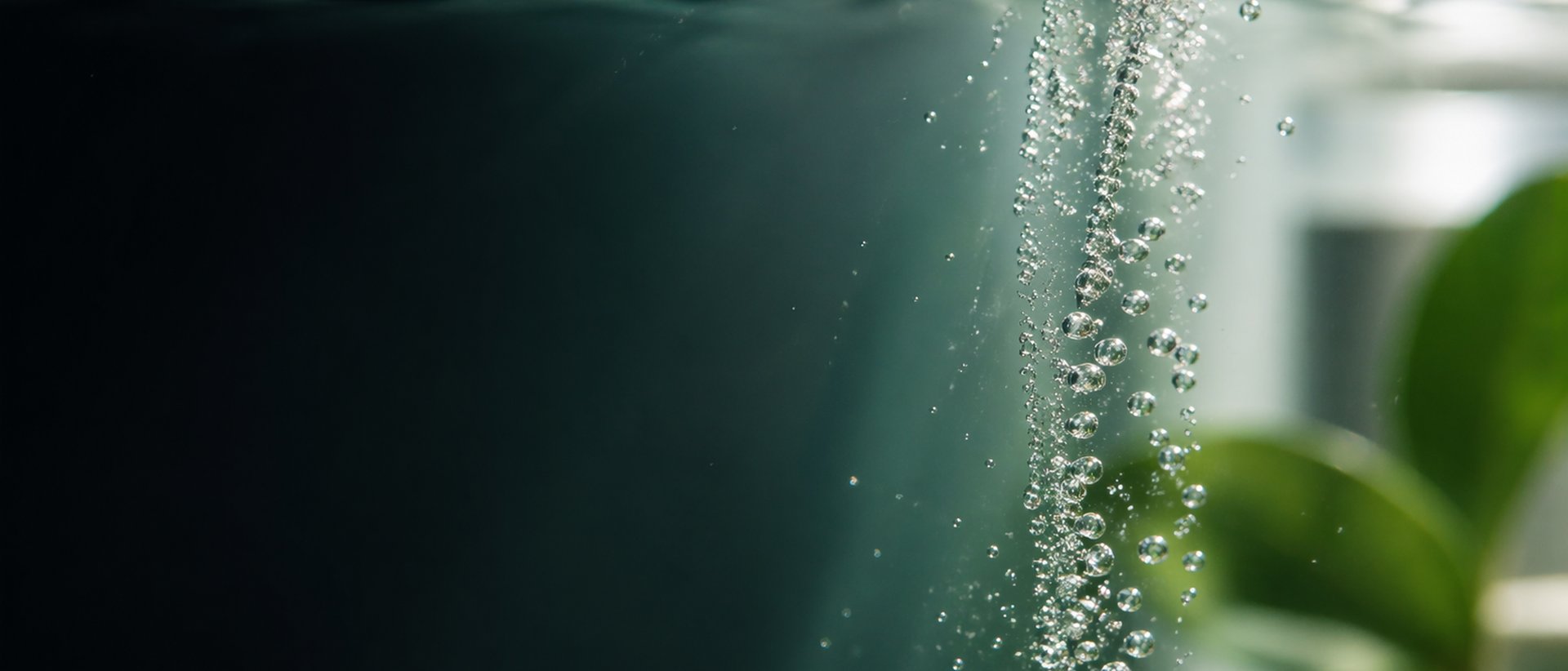 Bulles de CO2 montant dans l'eau claire devant une cuisine bruxelloise lumineuse · traitement anti-calcaire écologique sans sel ni rejet